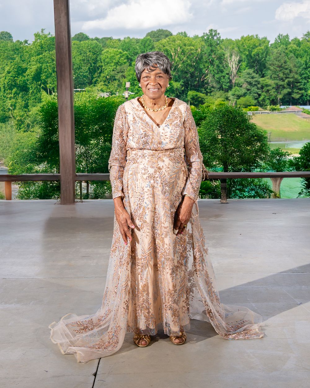 Josephine Sims Mitchell in a gold gown, standing on an outdoor pavilion
